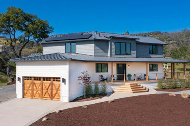 Ejemplo de fachada de casa blanca y gris de estilo de casa de campo extra grande de dos plantas con revestimiento de vinilo, tejado de un solo tendido y tejado de metal