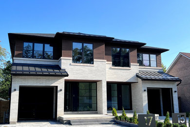 Mittelgroße, Zweistöckige Moderne Doppelhaushälfte mit Backsteinfassade, weißer Fassadenfarbe, Satteldach, Blechdach und schwarzem Dach in Toronto