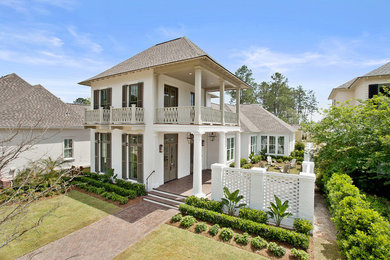 Mid-sized beach style two-storey stucco beige exterior in New Orleans with a hip roof.