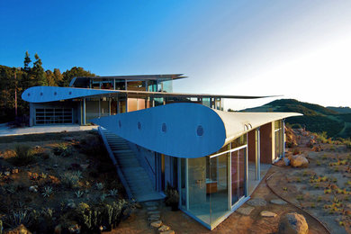 Trendy three-story glass exterior home photo in Los Angeles