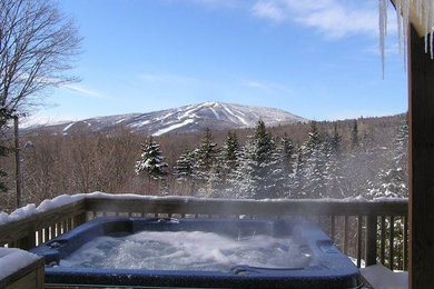 Example of a backyard hot tub design in Denver with decking