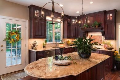 Large elegant l-shaped brown floor and dark wood floor eat-in kitchen photo in San Francisco with a drop-in sink, raised-panel cabinets, dark wood cabinets, granite countertops, beige backsplash, stone tile backsplash, stainless steel appliances, an island and beige countertops