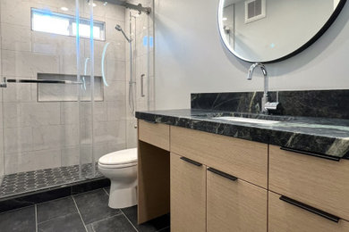 Inspiration for a mid-sized contemporary 3/4 white tile and porcelain tile porcelain tile, black floor and single-sink bathroom remodel in San Francisco with flat-panel cabinets, medium tone wood cabinets, a one-piece toilet, gray walls, an undermount sink, soapstone countertops, green countertops, a niche and a built-in vanity