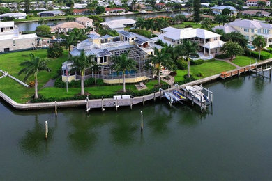 Huge tropical yellow three-story mixed siding exterior home idea in Tampa with a hip roof