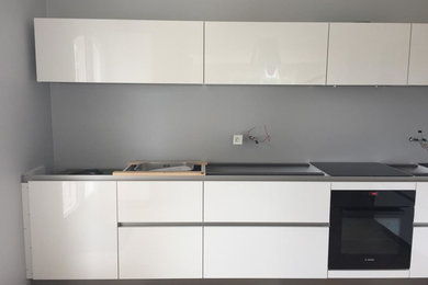 Inspiration for a mid-sized modern l-shaped separate kitchen in Grenoble with an undermount sink, white cabinets, marble benchtops and black appliances.