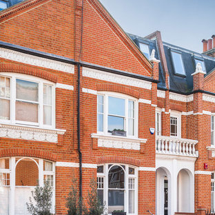 ロンドンのトラディショナルスタイルのおしゃれな家の外観 (レンガサイディング、赤い外壁) の写真
