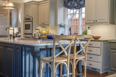 Example of a classic l-shaped dark wood floor open concept kitchen design in Dallas with raised-panel cabinets, beige cabinets, granite countertops, white backsplash, subway tile backsplash, stainless steel appliances and an island