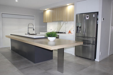 This is an example of a mid-sized contemporary galley open plan kitchen in Canberra - Queanbeyan with an undermount sink, grey cabinets, quartz benchtops, marble splashback, porcelain floors, with island, grey floor and white benchtop.