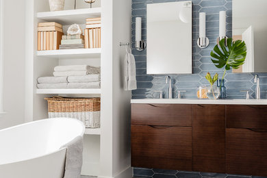 This is an example of a contemporary master bathroom in Boston with flat-panel cabinets, dark wood cabinets, a freestanding tub, an alcove shower, blue tile, grey floor, white walls and an undermount sink.