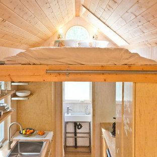 Modelo de dormitorio tipo loft, actual, pequeño, sin chimenea, con paredes blancas y suelo de madera en tonos medios