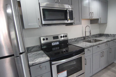 Inspiration for a small modern medium tone wood floor and gray floor eat-in kitchen remodel in Baltimore with an undermount sink, shaker cabinets, gray cabinets, granite countertops, stainless steel appliances and gray countertops