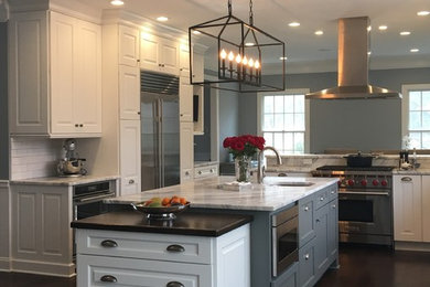 Inspiration for a large l-shaped dark wood floor eat-in kitchen remodel in New York with an undermount sink, raised-panel cabinets, white cabinets, marble countertops, white backsplash, subway tile backsplash, stainless steel appliances and an island