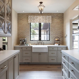 Traditional kitchen pantry remodeling - Example of a classic u-shaped medium tone wood floor and brown floor kitchen pantry design in San Francisco with a farmhouse sink, recessed-panel cabinets, gray cabinets, gray backsplash and no island