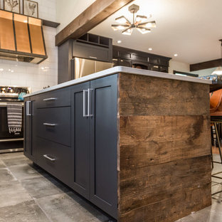 Стильный дизайн: большая угловая кухня в стиле лофт с кладовкой, врезной раковиной, плоскими фасадами, черными фасадами, столешницей из кварцевого композита, белым фартуком, фартуком из керамогранитной плитки, техникой из нержавеющей стали, полом из цементной плитки, островом, серым полом и белой столешницей - последний тренд