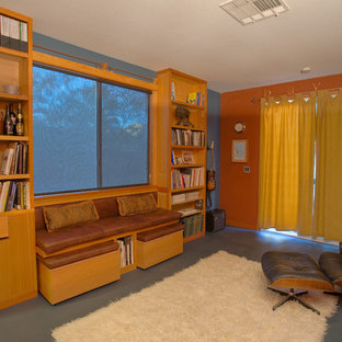 Photo of a small modern home studio in Las Vegas with orange walls, concrete flooring and a freestanding desk.