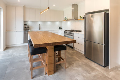 Inspiration for a mid-sized industrial l-shaped eat-in kitchen in Adelaide with an undermount sink, flat-panel cabinets, white cabinets, quartz benchtops, white splashback, mosaic tile splashback, stainless steel appliances, cement tiles, with island, grey floor and white benchtop.