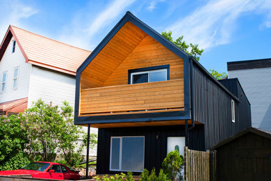 Diseño de fachada de casa negra y negra minimalista pequeña de dos plantas con revestimiento de metal, tejado a cuatro aguas, tejado de metal y panel y listón