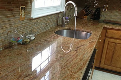 Mid-sized eat-in kitchen photo in Baltimore with a single-bowl sink, medium tone wood cabinets, granite countertops, multicolored backsplash, glass tile backsplash and stainless steel appliances