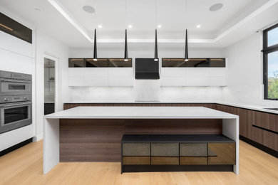 Photo of a large modern galley open plan kitchen in San Francisco with a submerged sink, flat-panel cabinets, white cabinets, engineered stone countertops, white splashback, engineered quartz splashback, stainless steel appliances, an island, beige floors and white worktops.