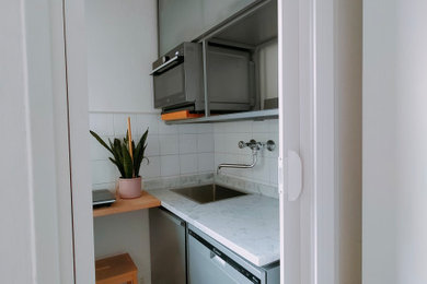 Photo of a small contemporary single-wall open plan kitchen in Milan with a drop-in sink, louvered cabinets, grey cabinets, marble benchtops, white splashback, ceramic splashback, stainless steel appliances, terrazzo floors, no island, multi-coloured floor and white benchtop.