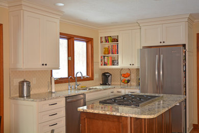 Inredning av ett klassiskt mellanstort grå grått kök, med en undermonterad diskho, luckor med infälld panel, vita skåp, granitbänkskiva, beige stänkskydd, stänkskydd i porslinskakel, rostfria vitvaror, mellanmörkt trägolv, en köksö och brunt golv