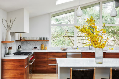 Photo of a large contemporary l-shaped eat-in kitchen in New York with a single-bowl sink, flat-panel cabinets, marble benchtops, white splashback, marble splashback, stainless steel appliances, light hardwood floors, a peninsula, beige floor, white benchtop and medium wood cabinets.