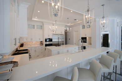 This is an example of a large transitional u-shaped open plan kitchen in Miami with a farmhouse sink, beaded inset cabinets, white cabinets, quartz benchtops, white splashback, marble splashback, stainless steel appliances, marble floors, with island and white floor.