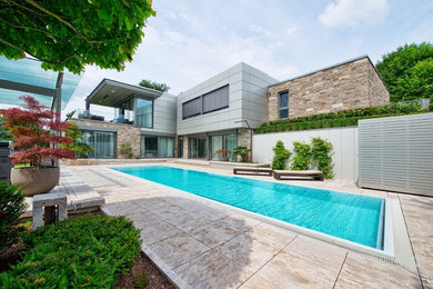 Photo of a large modern backyard rectangular aboveground pool in Frankfurt with natural stone pavers.