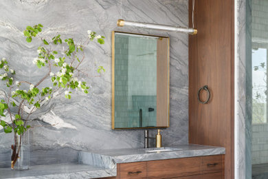 カルガリーにあるラグジュアリーな広いインダストリアルスタイルのおしゃれなマスターバスルーム (中間色木目調キャビネット、置き型浴槽、洗面台2つ、フローティング洗面台) の写真