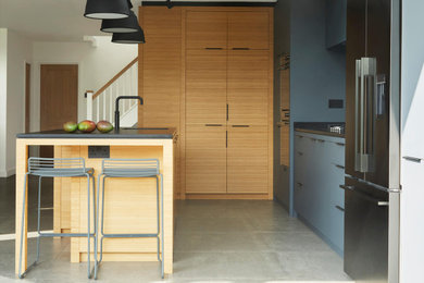 На фото: угловая кухня среднего размера в стиле модернизм с обеденным столом, плоскими фасадами и островом