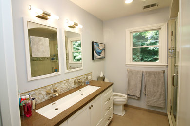 Photo of a transitional bathroom in San Francisco with an alcove shower, gray tile, blue walls, an undermount sink, brown floor and a hinged shower door.