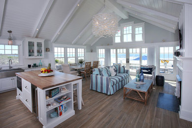 Inspiration for a beach style open plan dining in Philadelphia with white walls, medium hardwood floors, a standard fireplace, a stone fireplace surround and brown floor.