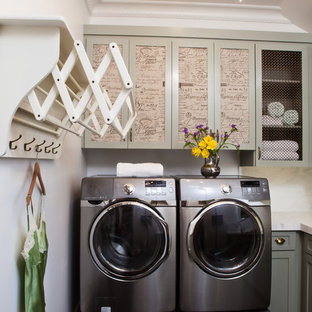 サンフランシスコのトラディショナルスタイルのおしゃれな洗濯室 (落し込みパネル扉のキャビネット、左右配置の洗濯機・乾燥機、黒い床) の写真