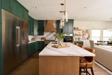 Example of a mid-sized transitional l-shaped vinyl floor and brown floor open concept kitchen design in Los Angeles with an undermount sink, shaker cabinets, green cabinets, quartz countertops, white backsplash, quartz backsplash, stainless steel appliances, an island and white countertops