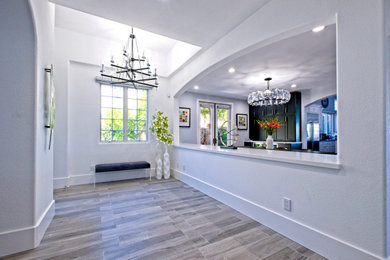 Inspiration for a large modern foyer in Orange County with white walls, porcelain floors and beige floor.