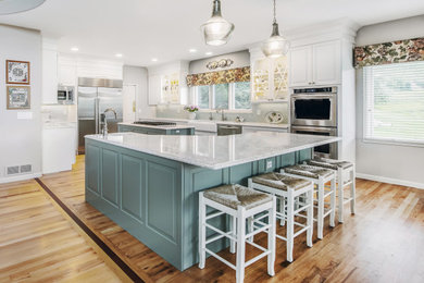 Example of a large french country medium tone wood floor and brown floor kitchen design in Denver with a farmhouse sink, raised-panel cabinets, white cabinets, quartzite countertops, green backsplash, porcelain backsplash, stainless steel appliances and two islands