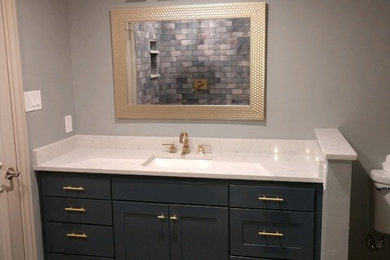 Example of a large transitional 3/4 porcelain tile and gray floor bathroom design in Dallas with shaker cabinets, blue cabinets, a two-piece toilet, gray walls, an undermount sink, quartz countertops and white countertops