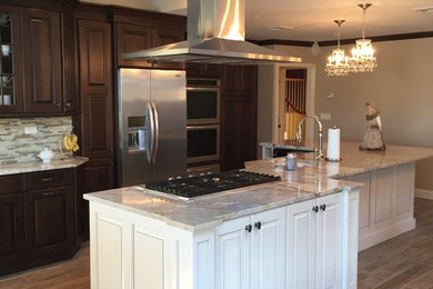 Large trendy l-shaped dark wood floor eat-in kitchen photo in New York with a farmhouse sink, raised-panel cabinets, dark wood cabinets, quartz countertops, multicolored backsplash, matchstick tile backsplash, stainless steel appliances and an island