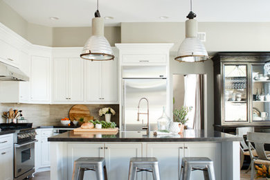 Open concept kitchen - large transitional l-shaped light wood floor open concept kitchen idea in Orange County with a farmhouse sink, beaded inset cabinets, white cabinets, beige backsplash, stone tile backsplash, stainless steel appliances and an island