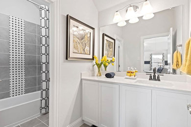 Photo of a contemporary bathroom in Dallas with recessed-panel cabinets, white cabinets, an alcove bath, a shower/bath combination, grey tiles, white walls, porcelain flooring, an integrated sink, grey floors, a shower curtain, white worktops, a single sink and a built in vanity unit.