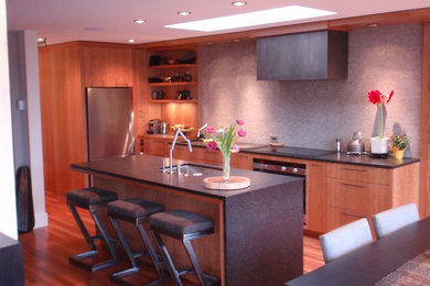 Example of a mid-sized minimalist l-shaped light wood floor and brown floor eat-in kitchen design in Orange County with an undermount sink, flat-panel cabinets, light wood cabinets, soapstone countertops, gray backsplash, stainless steel appliances, an island and mosaic tile backsplash