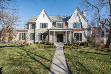 This is an example of a large transitional two-storey grey house exterior in Chicago with stone veneer and a tile roof.