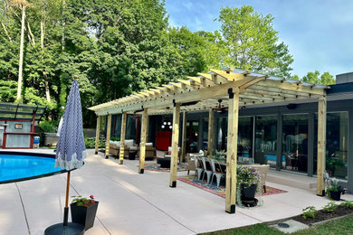 Mid-sized 1950s backyard concrete patio photo in Grand Rapids with a pergola