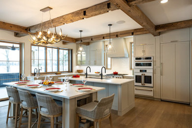 Eat-in kitchen - large transitional l-shaped light wood floor, brown floor and exposed beam eat-in kitchen idea in Other with an undermount sink, shaker cabinets, beige cabinets, quartz countertops, white backsplash, ceramic backsplash, white appliances, an island and white countertops