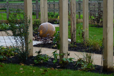 Mittelgroßer, Halbschattiger Landhaus Garten im Frühling, hinter dem Haus mit Wasserspiel und Natursteinplatten in West Midlands