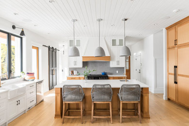 This is an example of a large transitional kitchen in Other with a farmhouse sink, shaker cabinets, medium wood cabinets, grey splashback, panelled appliances, medium hardwood floors, with island, brown floor, white benchtop and timber.