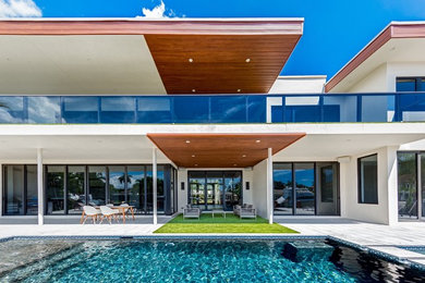 Inspiration for a large contemporary two-storey stucco white house exterior in Miami with a flat roof.