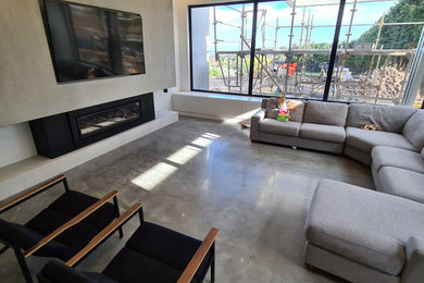 Photo of a mid-sized contemporary enclosed living room in Melbourne with white walls, concrete floors, a standard fireplace, a concrete fireplace surround and grey floor.