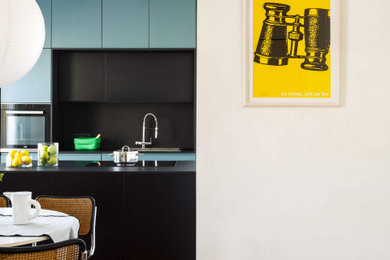 Esempio di una cucina minimal di medie dimensioni con lavello da incasso, ante a filo, ante turchesi, elettrodomestici in acciaio inossidabile e top nero