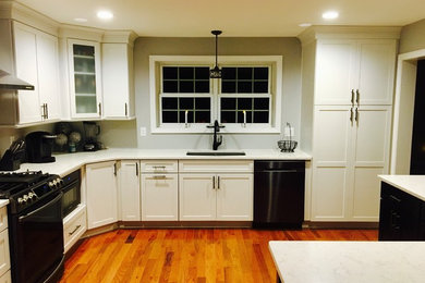 Transitional l-shaped medium tone wood floor eat-in kitchen photo in Manchester with an undermount sink, shaker cabinets, white cabinets, quartz countertops, blue backsplash, black appliances and an island